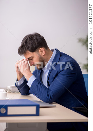 Young male employee sitting at workplace Young male employee sitting at workplace 101521377