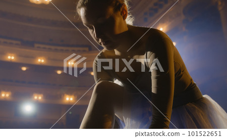 Ballerina in dress putting on and tying pointe shoes Ballerina in dress putting on and tying pointe shoes 101522651