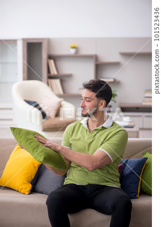 Young man with a lot of pillows sitting on the sofa 101523436