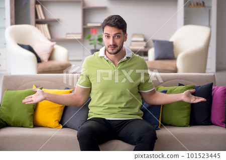 Young man with a lot of pillows sitting on the sofa Young man with a lot of pillows sitting on the sofa 101523445