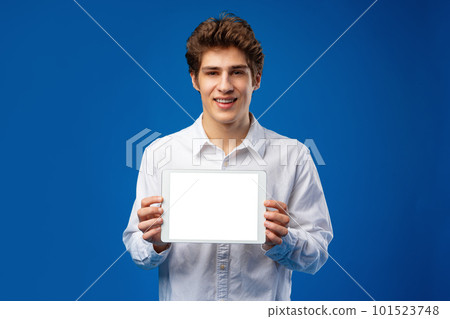 Happy young man showing digital tablet isolated on blue background. 101523748