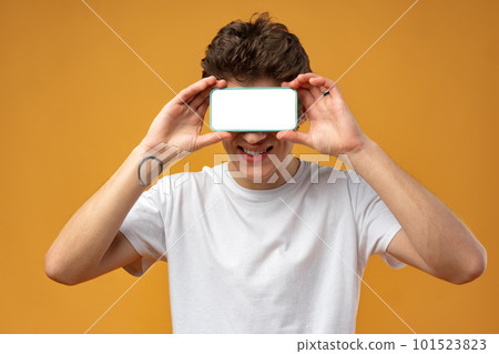 Smiling young man showing mobile phone blank white screen mockup to camera. Smiling young man showing mobile phone blank white screen mockup to camera. 101523823