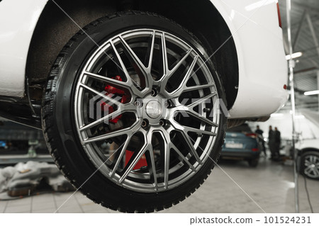 Car on a hoist in repair workshop with focus on the wheel Car on a hoist in repair workshop with focus on the wheel 101524231