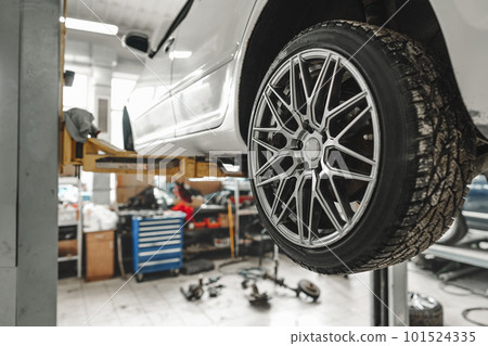Car on a hoist in repair workshop with focus on the wheel 101524335