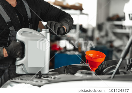 Close up of car service worker pouring new oil into car engine 101524877
