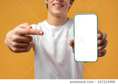 Smiling young man showing mobile phone blank white screen mockup to camera. 101524966