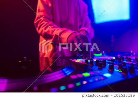 Hands of a DJ creating and regulating music on dj console mixer at club concert 101525189
