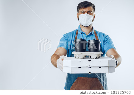 Delivery man in protective mask and medical gloves holding takeaway food. Compliance with the hygiene rules while covid-19 pandemic 101525703