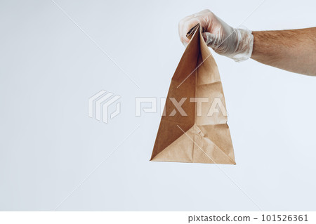 Courier hands in latex gloves giving packed food delivery 101526361