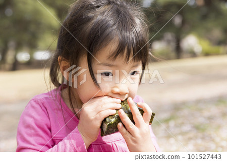 A girl who eats onigiri at the park 101527443