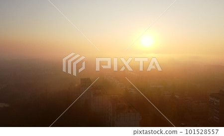 Dawn Sunrise in city scene. Bright shining sun at dawn, fog over rooftops of multi-storey buildings. Top view of many houses town. Landscape. Cityscape, urban scenery. Aerial drone view. Dawn Sunrise in city scene. Bright shining sun at dawn, fog over rooftops of multi-storey buildings. Top view of many houses town. Landscape. Cityscape, urban scenery. Aerial drone view. 101528557