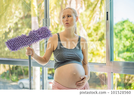 Pregnant woman washes the floor and is tired. Tired pregnant woman having pain in back while she is cleaning her house Pregnant woman washes the floor and is tired. Tired pregnant woman having pain in back while she is cleaning her house 101528560