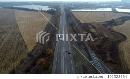 Landscape Highway, driving cars, agricultural fields after harvest, lakes on autumn day. Flying over automobile asphalt road with white markings and many cars. Perspective scenery. Aerial drone view Landscape Highway, driving cars, agricultural fields after harvest, lakes on autumn day. Flying over automobile asphalt road with white markings and many cars. Perspective scenery. Aerial drone view 101528564