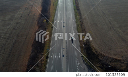 Cars driving along the highway on an autumn sunny day. Automobile road with white markings between agricultural fields. View of the cars driving on paved road. automobile vehicles. Aerial drone view. 101528609