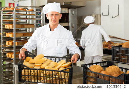 Male baker carrying crate with baked bread Male baker carrying crate with baked bread 101530642