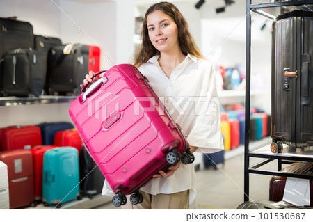 Satisfied girl in a shop, holding a travel suitcase Satisfied girl in a shop, holding a travel suitcase 101530687