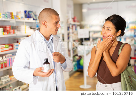 Woman complaining about toothache to pharmacist Woman complaining about toothache to pharmacist 101530716