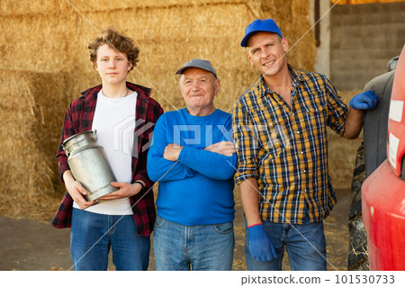 Successful elderly dairy farm owner with adult son and teen grandson standing in hayloft 101530733