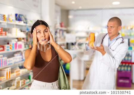 Oriental woman complaining about headache in chemist shop 101530741