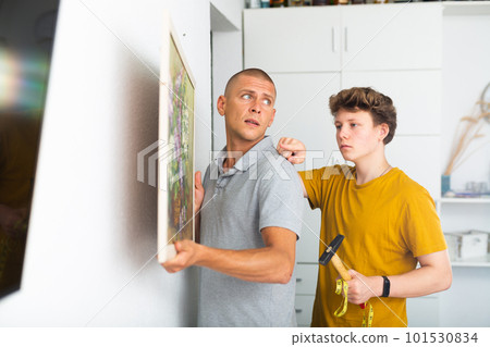 Father and his son hanging picture on wall 101530834