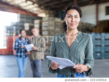 Portrait of woman worker standing with papers near crates with peaches in warehouse Portrait of woman worker standing with papers near crates with peaches in warehouse 101530918