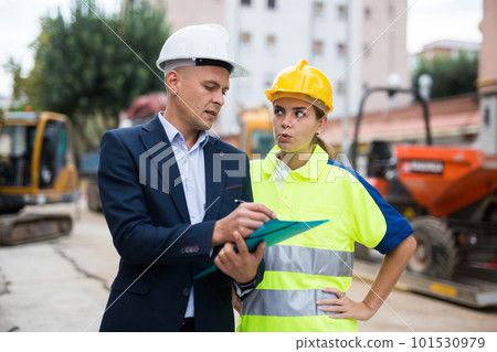 Male and female engineers in construction area 101530979