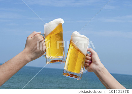 Cheers with beer in front of the blue sky and the sea 101531878