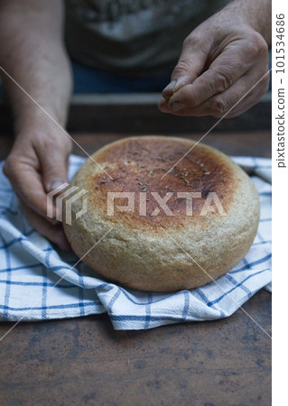 Homemade crusty loave of bread on wooden background. Baker holding fresh bread in the hands. view from above. Dark mood Homemade crusty loave of bread on wooden background. Baker holding fresh bread in the hands. view from above. Dark mood 101534686