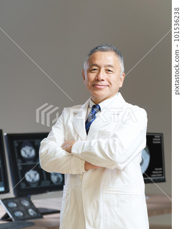 A senior man in a white coat who folds his arms in front of the monitor A senior man in a white coat who folds his arms in front of the monitor 101536238