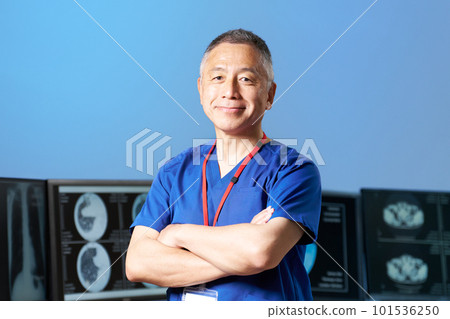A senior man wearing a scrub who looks while folding his arms A senior man wearing a scrub who looks while folding his arms 101536250