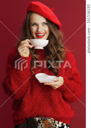smiling stylish female in red sweater and beret with tea cup 101536285