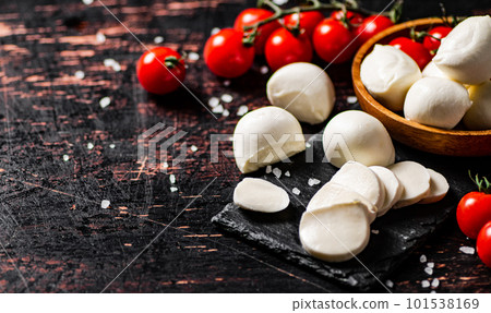 Sliced mozzarella on a stone board with tomatoes. 101538169