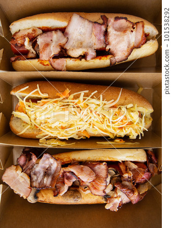 American hot dog with different flavors, with cheese and crispy onions on a white table in a minimalist style. Fast food, takeaway food, food for motorists. Hot dog sandwich with sausage, vertical American hot dog with different flavors, with cheese and crispy onions on a white table in a minimalist style. Fast food, takeaway food, food for motorists. Hot dog sandwich with sausage, vertical 101538292
