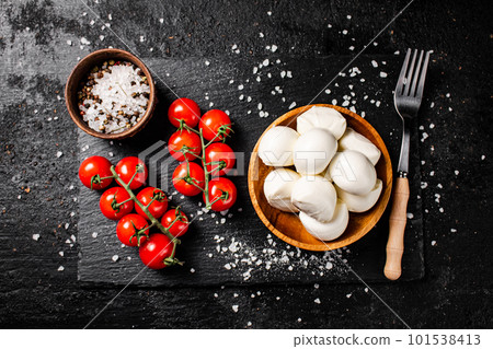 Mozzarella cheese in a plate on a stone board with tomatoes and spices. 101538413
