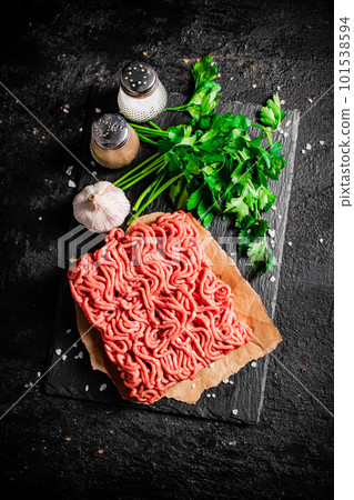 Minced meat on a stone board with parsley and garlic. Minced meat on a stone board with parsley and garlic. 101538594