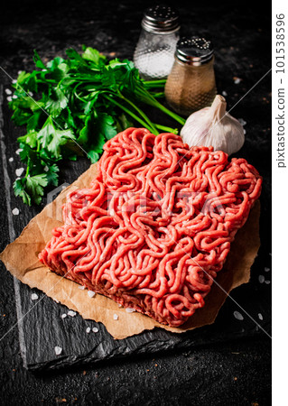 Minced meat on a stone board with parsley and garlic. 101538596