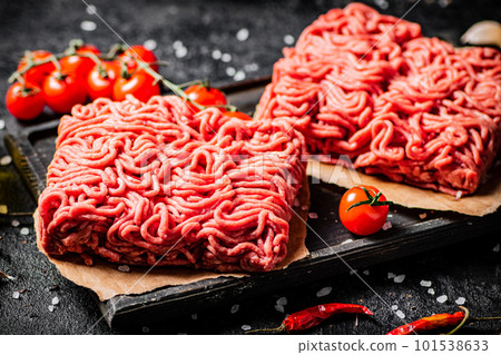 Raw minced meat on a cutting board with cherry tomatoes. Raw minced meat on a cutting board with cherry tomatoes. 101538633