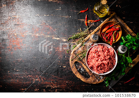 Fresh minced meat on a cutting board with parsley and chili pepper pods. 101538670