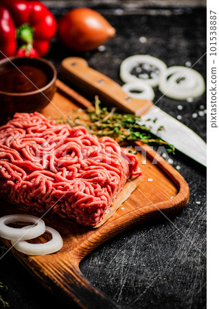 Minced meat on a wooden cutting board with onions and sprigs of thyme. Minced meat on a wooden cutting board with onions and sprigs of thyme. 101538887