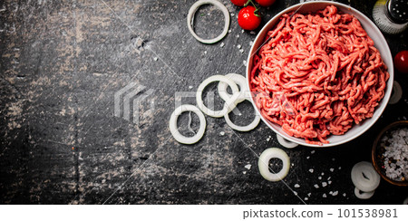 Minced meat in a bowl with onion rings, tomatoes and spices. Minced meat in a bowl with onion rings, tomatoes and spices. 101538981