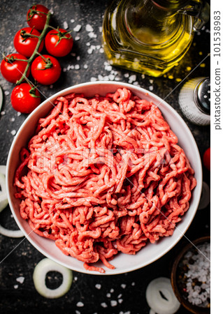 Minced meat in a bowl with onion rings, tomatoes and spices. Minced meat in a bowl with onion rings, tomatoes and spices. 101538983