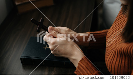 Woman sitting and studying the scriptures.The wooden cross in the hands. Christian education concepts The Holy Scriptures open Woman sitting and studying the scriptures.The wooden cross in the hands. Christian education concepts The Holy Scriptures open 101539033