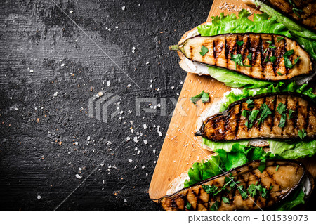 Sandwich with grilled eggplant and lettuce on a wooden cutting board. Sandwich with grilled eggplant and lettuce on a wooden cutting board. 101539073