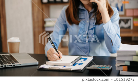 Business woman have the joy of talking on the smartphone and writing on the notepad in modern office 101539272