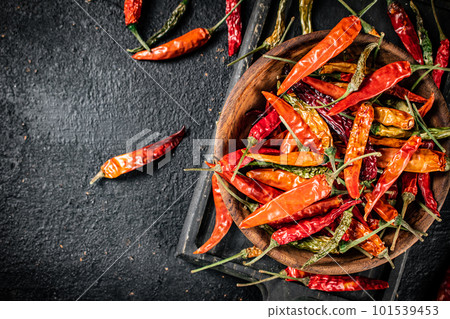 Multicolored pods of dried chili peppers on a cutting board. 101539453