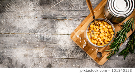 A tin can of canned corn on a cutting board. A tin can of canned corn on a cutting board. 101540138