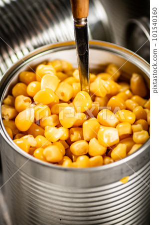 An open can of canned corn with a spoon. 101540160