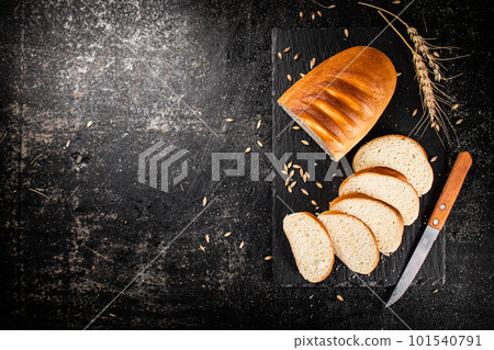 Sliced wheat bread with a knife on a stone board. Sliced wheat bread with a knife on a stone board. 101540791