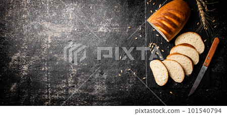 Sliced wheat bread with a knife on a stone board. 101540794