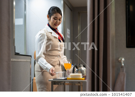 Airplane flight attendant preparing food and drinks for passengers on board. 101541407